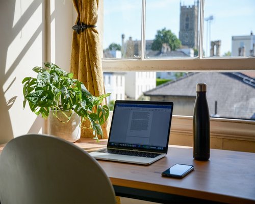 A neat and comfortable home office desk setup with a laptop and a warm cup of tea