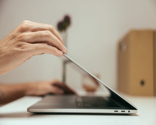 A person closing their laptop at the end of the workday, signaling the start of evening rest
